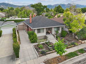 View of front of home featuring a vegetable garden, a chimney, a shingled roof, a mountain view, and a detached garage