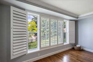 Empty room with healthy amount of natural light, wood finished floors, and crown molding