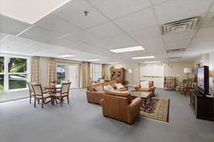 Carpeted living area featuring a paneled ceiling