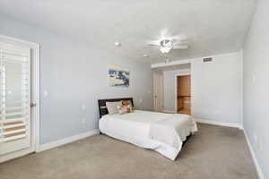 Carpeted bedroom with a textured ceiling and a ceiling fan