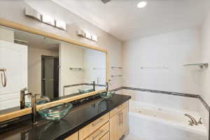 Bathroom featuring a jetted tub, double vanity, a stall shower, and a textured ceiling