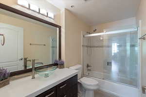 Bathroom featuring vanity, shower / bath combination with glass door, and a textured ceiling