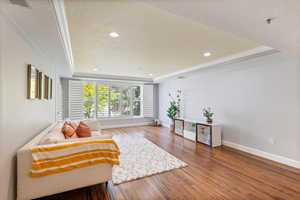 Sitting room with a tray ceiling, crown molding, wood finished floors, recessed lighting, and a textured ceiling
