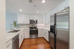Kitchen with stainless steel appliances, light countertops, white cabinets, backsplash, and recessed lighting