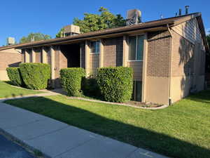 View of property exterior with brick siding and a lawn