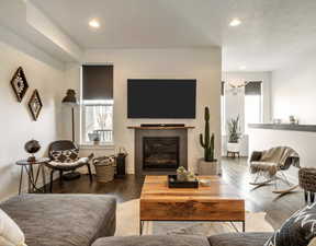 Living room with a tiled fireplace, wood finished floors, and recessed lighting