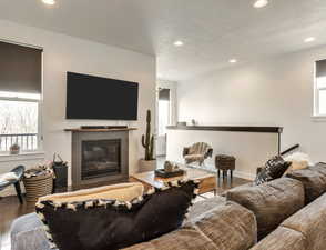 Living room with recessed lighting, wood finished floors, and a tiled fireplace