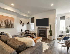 Living room with recessed lighting, dark wood-style flooring, and a glass covered fireplace