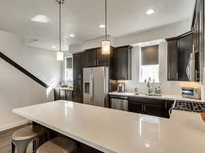 Kitchen featuring dark brown cabinets, a peninsula, hanging light fixtures, a kitchen bar, and recessed lighting