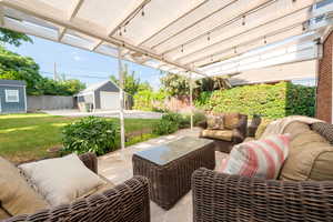 View of patio with an outdoor living space, detached garage and large storage shed.