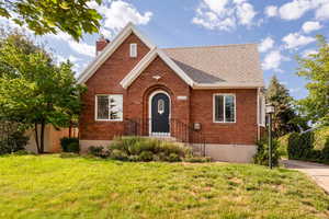 English style home with a detached garage, brick siding, an outbuilding, and a shingled roof