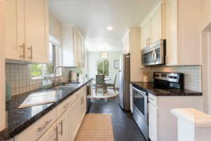 Kitchen with stainless steel appliances, , white cabinets, granite countertops, tile flooring and recessed lighting