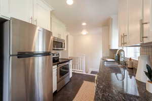Kitchen featuring stainless steel appliances, tasteful backsplash, granite countertops, white cabinets, tile flooring and recessed lighting
