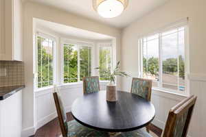 Dining area is flooded with natural light, dark wood finished floors.