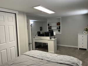 Carpeted bedroom with an office area and baseboards