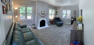 Carpeted living room with a fireplace with flush hearth and baseboards