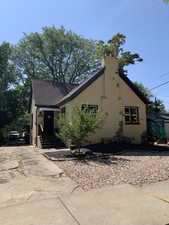 View of front of property with stucco siding, roof with shingles, a chimney, and concrete driveway