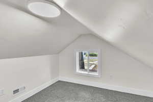 Bonus room featuring dark carpet and vaulted ceiling