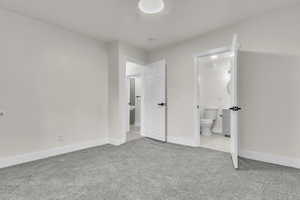 Unfurnished bedroom featuring carpet flooring and ensuite bath