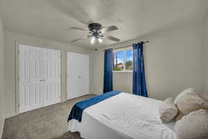 Bedroom with multiple closets, carpet, ceiling fan, and a textured ceiling