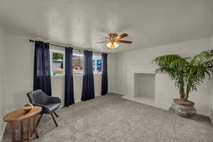 Living area featuring a ceiling fan, light colored carpet, and a textured ceiling