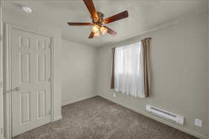 Carpeted spare room with a baseboard heating unit, a ceiling fan, a smoke detector, and a textured ceiling