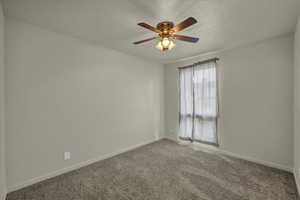Empty room with a textured ceiling, ceiling fan, and carpet flooring