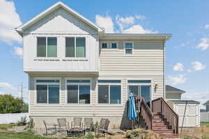 Back of house featuring a fire pit, a storage shed, and board and batten siding