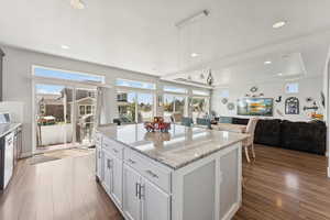 Kitchen with open floor plan, dark wood-style floors, a center island, light stone counters, and recessed lighting