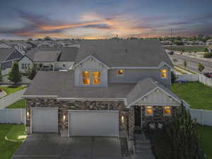 View of front of home featuring board and batten siding, concrete driveway, a shingled roof, and stone siding