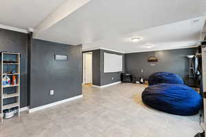 Home theater room with a textured ceiling, crown molding, and a textured wall