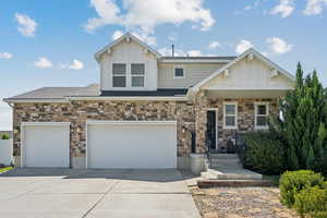 View of front of home featuring board and batten siding, concrete driveway, and stone siding