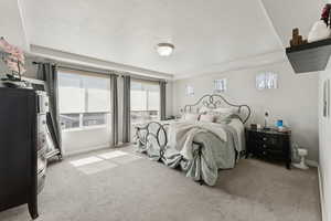 Bedroom with light colored carpet and a textured ceiling