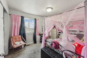 Carpeted bedroom featuring a textured ceiling and baseboards