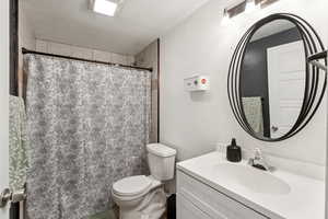 Full bathroom with vanity, a textured ceiling, and curtained shower