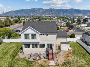 Back of property with a shed, board and batten siding, a mountain view, a fenced backyard, and roof with shingles