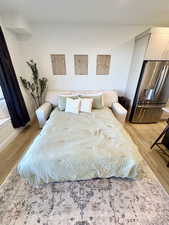 Bedroom with stainless steel fridge with ice dispenser and light wood-type flooring