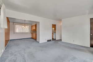 Unfurnished living room with a chandelier and carpet