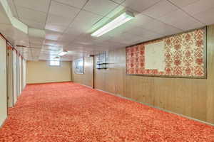 Basement featuring wooden walls and carpet flooring