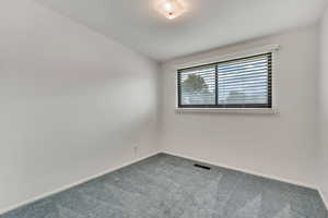 Carpeted empty room featuring baseboards and vaulted ceiling