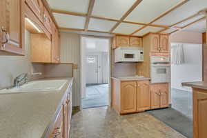 Kitchen with white appliances, light countertops, and light brown cabinets