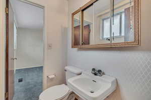 Half bathroom featuring a sink and wallpapered walls