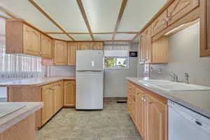 Kitchen with white appliances, light brown cabinetry, and light countertops