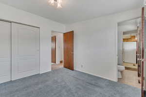 Unfurnished bedroom with a closet, ensuite bathroom, and carpet floors