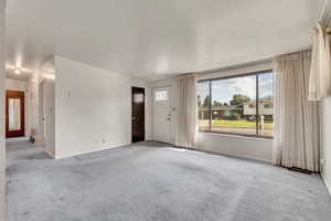 Unfurnished living room with carpet floors and baseboards