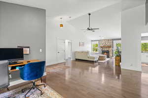 Home office with ceiling fan, a fireplace, wood finished floors, plenty of natural light, and high vaulted ceiling