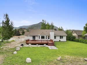 Back of house featuring a deck with mountain view, a chimney, and a patio