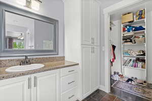 Bathroom with vanity, ceiling fan, and a walk in closet