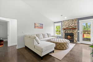Living area with a stone fireplace, wood finished floors, lofted ceiling, and recessed lighting