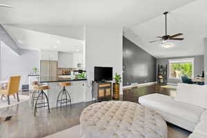 Living area featuring dark wood-type flooring, ceiling fan, high vaulted ceiling, and recessed lighting